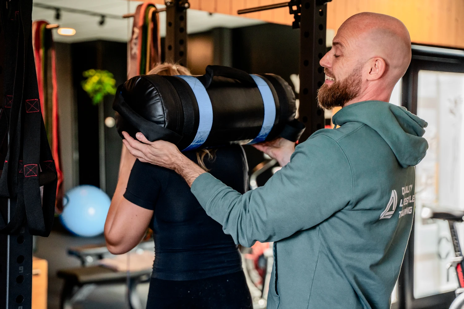 Personal trainer helpt klant bij krachttraining in de gym