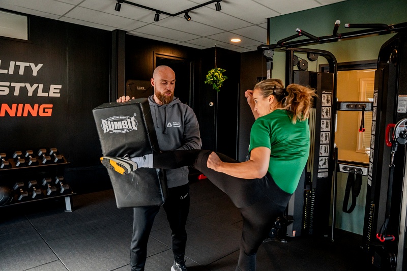 Personal trainer begeleidt klant tijdens training in de gym