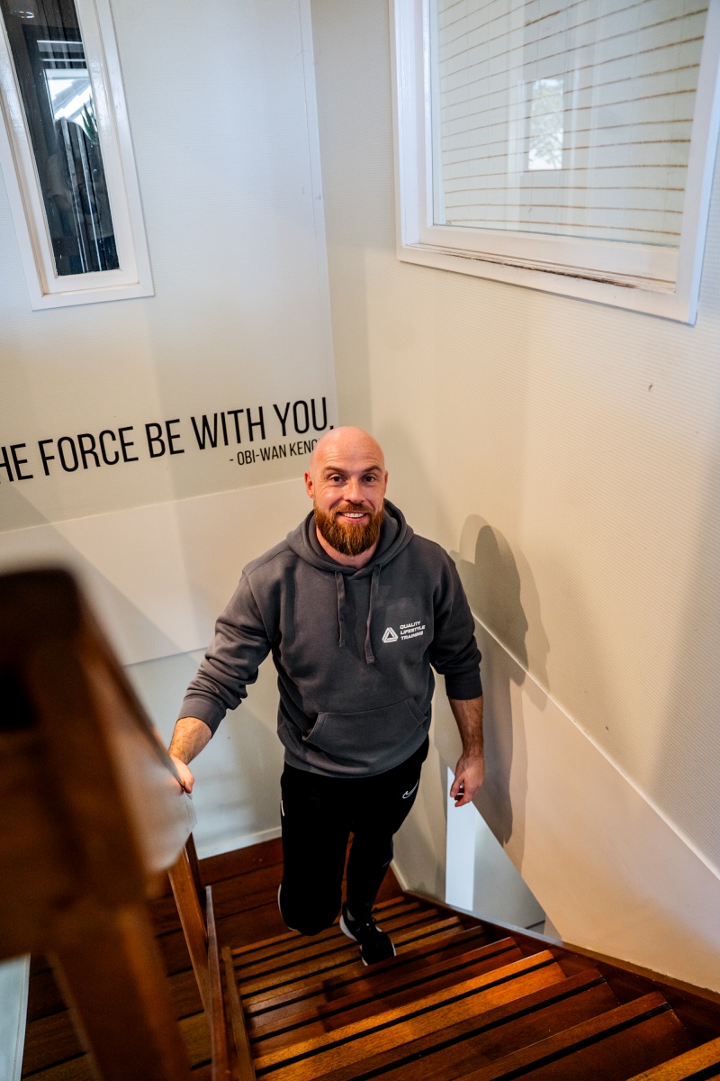 Gert-Jan staat in het trapgat, lachend en ontspannen vastgelegd.