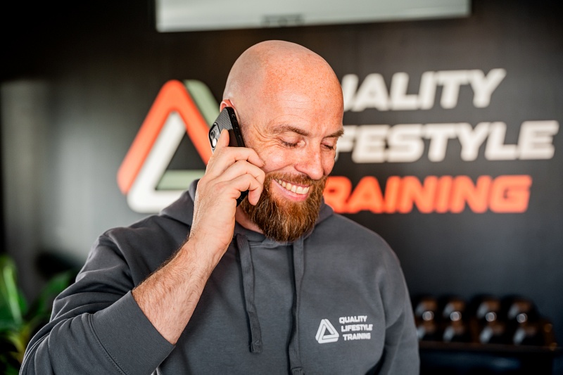 Gert-Jan aan de telefoon, lachend en ontspannen, met een open en toegankelijke uitstraling.